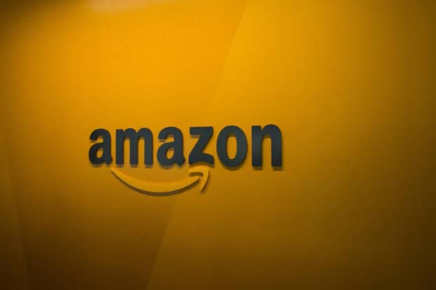 The Amazon Wallpapers logo is displayed on a yellow wall with shadow effects, 2K Desktop Wallpaper