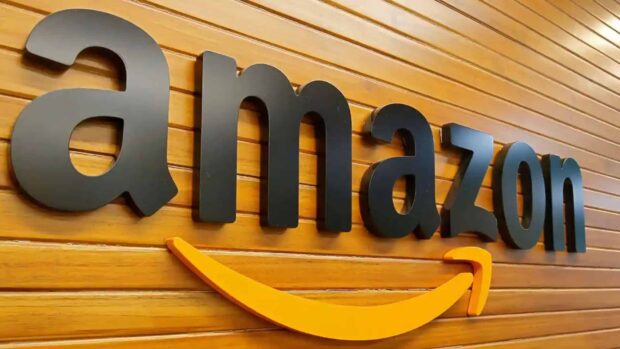 The Amazon logo sign is displayed prominently on a wooden slat wall in this image featuring Amazon Wallpapers, HD Desktop Wallpaper
