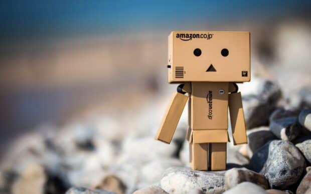 A small Amazon robot figure stands on gray rocks with a blurred background, 2K Desktop Wallpaper