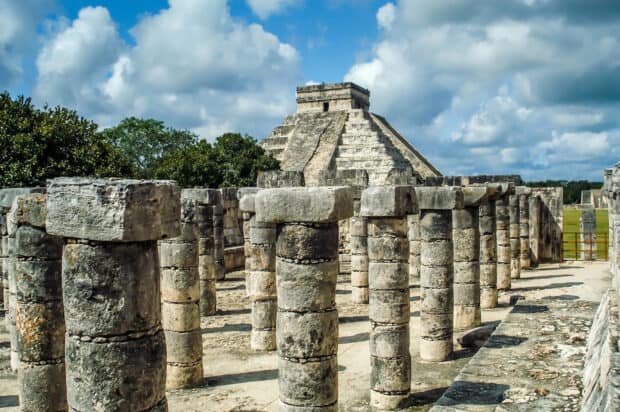 The ancient ruins of Chichen Itza feature stone columns and a pyramid under a blue sky, HD Desktop Wallpaper