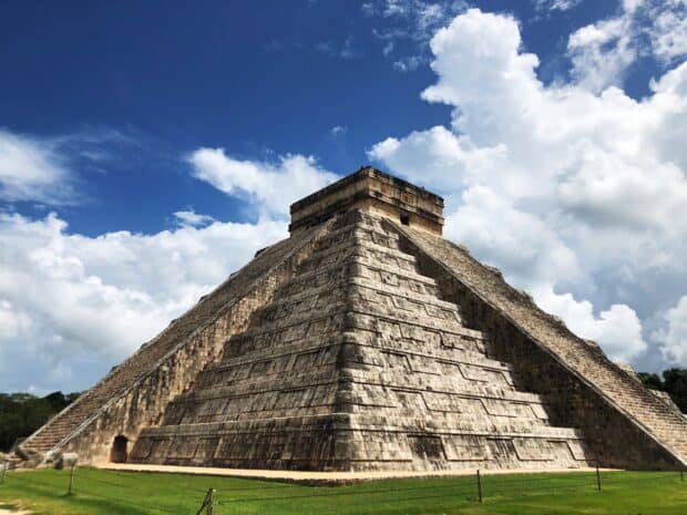 The Chichen Itza pyramid stands under a vibrant blue sky with clouds casting shadows, HD Desktop Wallpaper