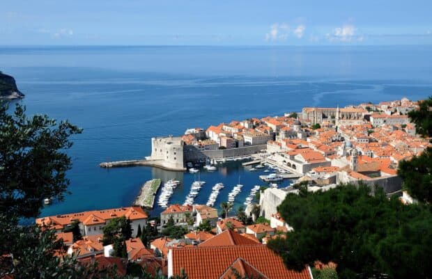 A scenic view of ancient city walls and harbor in Dubrovnik with red rooftops, 2K Desktop Wallpaper