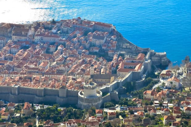 The ancient city walls in Dubrovnik surround the old town by the deep blue sea, Ancient City Walls Dubrovnik, 2K Desktop Wallpaper