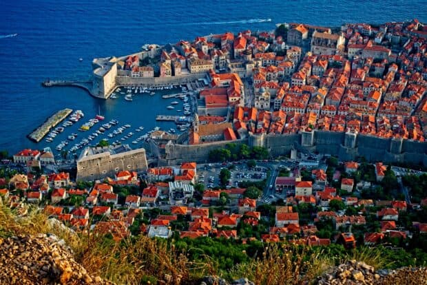 Aerial view of ancient city walls in Dubrovnik surrounded by vibrant buildings and the sea, HD Desktop Wallpaper