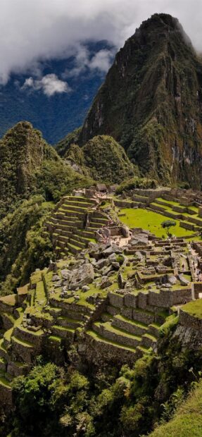 The Peru Wallpapers show the ancient Inca ruins surrounded by lush green mountains and cloudy skies, 2K Phone Wallpaper