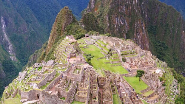 The ancient Inca city is surrounded by lush green mountains under a cloudy sky, 2K Desktop Wallpaper