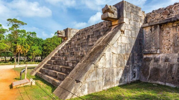 The ancient Chichen Itza ruins stand under a clear sky surrounded by greenery and stone structures, HD Desktop Wallpaper