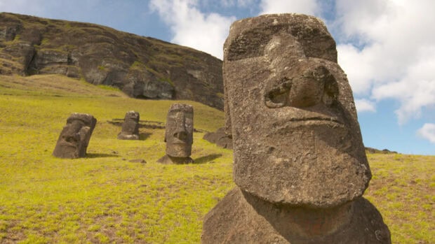 The iconic moai statues stand on a grassy hillside under a partly cloudy sky on Easter Island, HD Desktop Wallpaper
