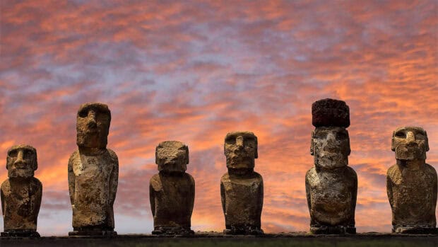 A row of ancient Moai statues stands tall at Easter Island against a dramatic sunset sky, HD Desktop Wallpaper