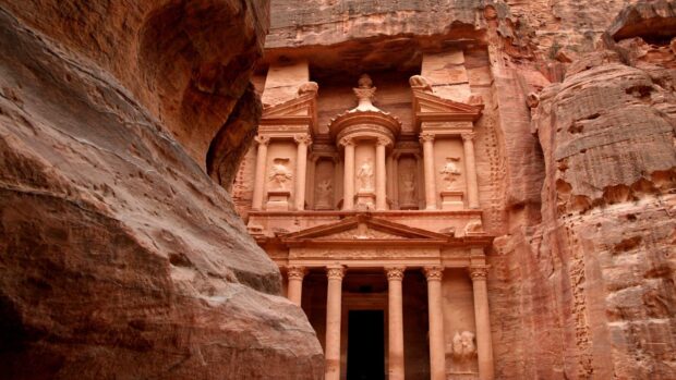 The ancient Petra carved rock facade is surrounded by rugged canyon walls under sunlight, HD Desktop Wallpaper