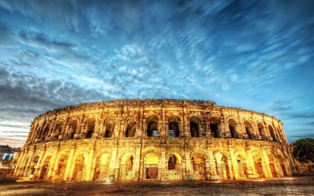 The ancient Roman Colosseum is illuminated at dusk under a dramatic blue sky, 2K Desktop Wallpaper