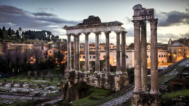 The ancient Roman ruins stand majestically with a glowing sunset sky in the background, 4K Desktop Wallpaper