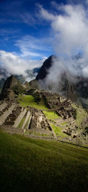 The image shows the ancient ruins surrounded by mountains and clouds in Peru with Peru Wallpapers, 2K Phone Wallpaper
