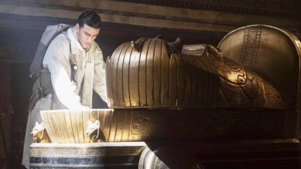 Jake Lockley carefully examines a golden ancient artifact inside a tomb, HD Desktop Wallpaper