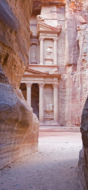 A detailed carved facade is visible through a narrow canyon in Petra Jordan, 2K Phone Wallpaper