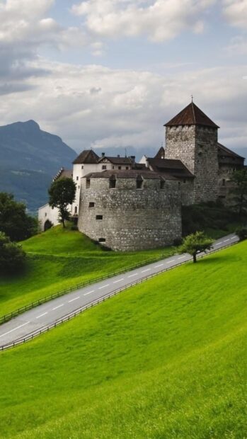 An ancient stone castle stands on a green hill under a cloudy sky in Liechtenstein wallpapers, HD Phone Wallpaper