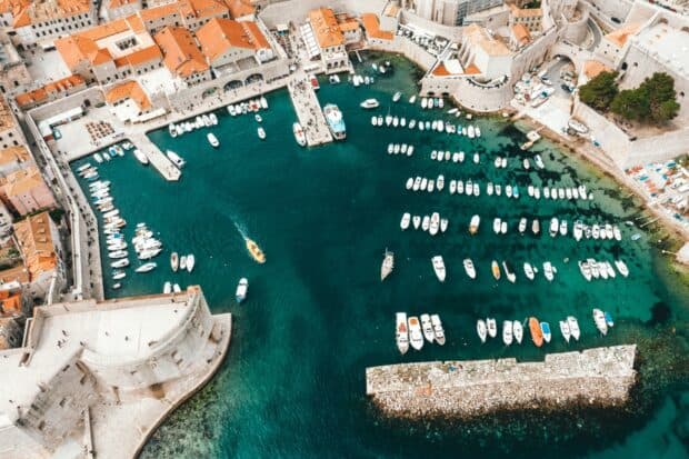 Aerial view of ancient city walls with boats docked in clear blue water of Dubrovnik, HD Desktop Wallpaper