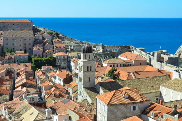 The ancient city walls of Dubrovnik overlook the terracotta rooftops and bright blue sea, 2K Desktop Wallpaper