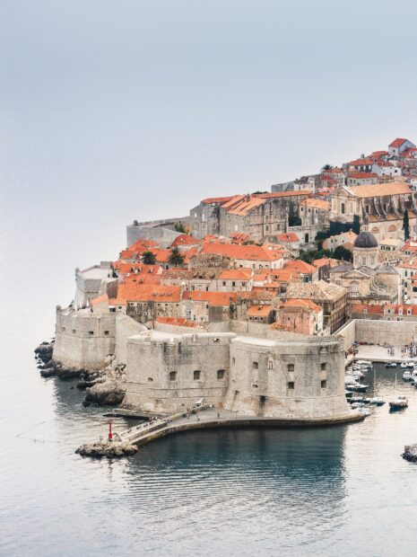 The ancient city walls of Dubrovnik stretch around the old town near the sea, HD Mobile Wallpaper