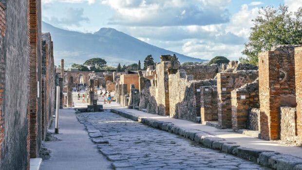 The Pompeii ruins show a stone paved street lined with old buildings under a blue sky, HD Desktop Wallpaper