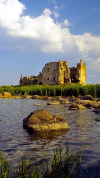The ancient ruins stand near water and green grass under a partly cloudy sky in Estonia, HD Phone Wallpaper
