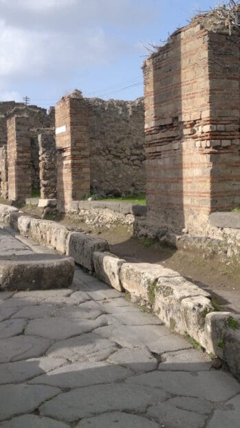 The stone pathway leads through ancient Pompeii ruins under a clear sky, HD Mobile Wallpaper