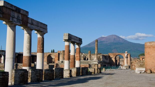 The Pompeii ruins stand before Mount Vesuvius under a clear blue sky in Pompeii Wallpapers, 4K Desktop Wallpaper