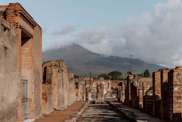 The Pompeii ruins show historic architecture under a cloudy sky with Mount Vesuvius in the background, HD Desktop Wallpaper