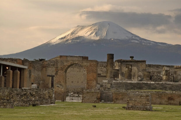 The Pompeii ruins are shown with Mount Vesuvius in the background under cloudy skies, 2K Desktop Wallpaper