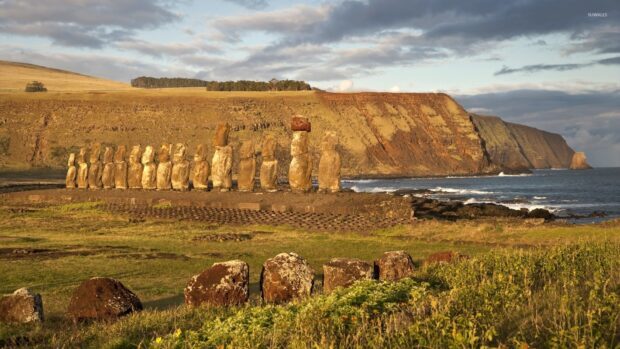 A row of iconic Easter Island statues stands along the coastline with cliffs and ocean waves in the background, HD Desktop Wallpaper