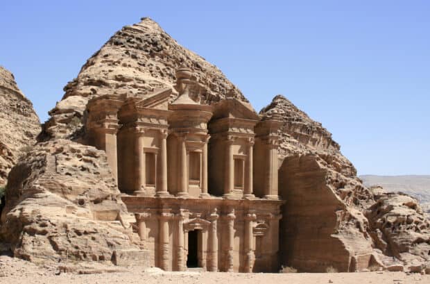 The ancient stone monastery in Petra Jordan is carved into cliffs under a clear blue sky, 2K Desktop Wallpaper