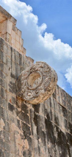 The ancient stone ring is prominently mounted on the weathered Chichen Itza wall under a bright sky, 2K Mobile Wallpaper
