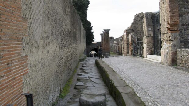 A narrow street with stone ruins and ancient walls in Pompeii is shown in this image, HD Desktop Wallpaper