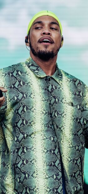 Anderson Paak is performing wearing a green patterned jacket and a yellow headband, 2K Phone Wallpaper