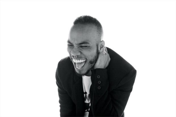 Anderson Paak laughs joyfully wearing a dark coat with a white background, 2K Desktop Wallpaper