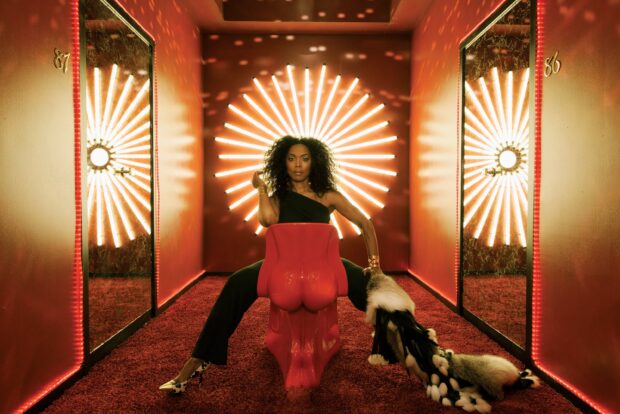 Angela Bassett is seated in a creative room with radiant light decorations, 2K Desktop Wallpaper