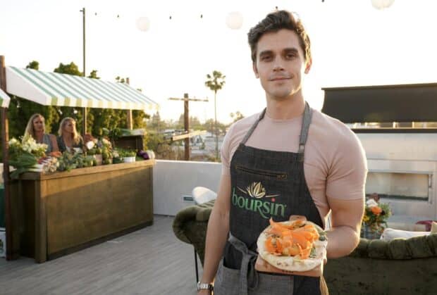 Antoni Porowski is standing outdoors holding a plate with a flatbread topped with vegetables, HD Desktop Wallpaper