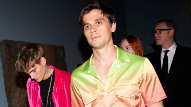 Antoni Porowski wears a vibrant green and orange shirt at an event with other people, HD Desktop Wallpaper