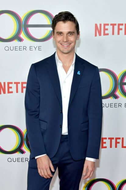 Antoni Porowski smiles confidently while wearing a navy suit on a Queer Eye event red carpet, 2K Mobile Wallpaper