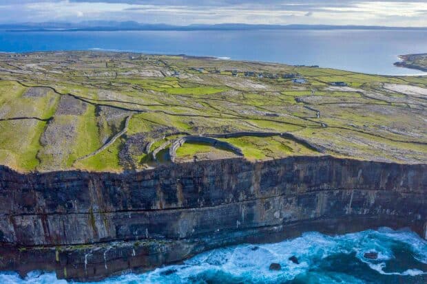 The Aran Islands show rugged cliffs and green fields meeting the ocean under a cloudy sky, HD Desktop Wallpaper