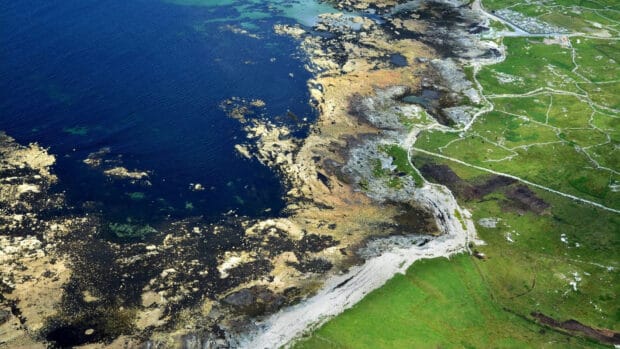 Aerial view of The Aran Islands coastline with rocky shores and green fields, HD Desktop Wallpaper