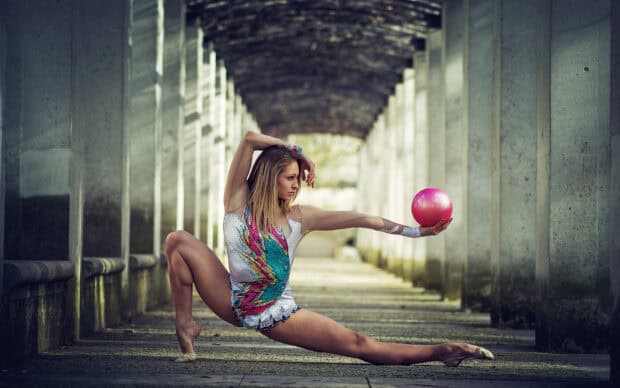 A gymnast performs an artistic pose holding a pink ball during rhythmic gymnastics, HD Desktop Wallpaper