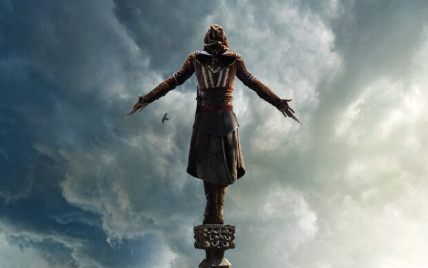 A character from Assassins Creed movie stands with arms outstretched on a pillar under a cloudy sky, 2K Desktop Wallpaper