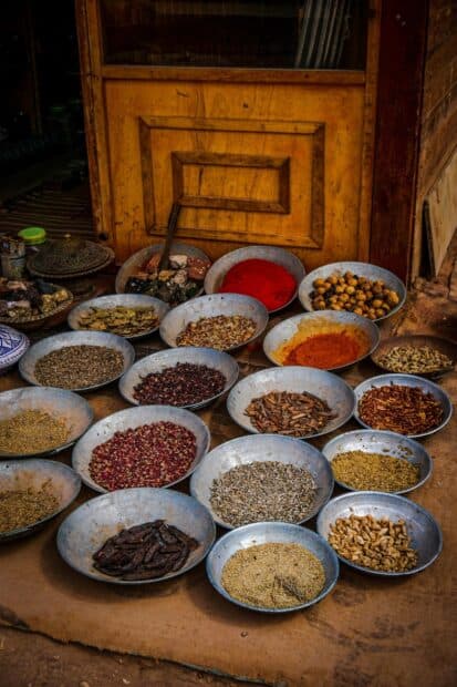 Various seasoning spices displayed in bowls on the ground near a wooden door, HD Mobile Wallpaper