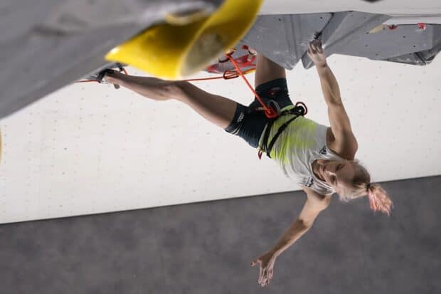 A female athlete is climbing an indoor rock wall with focus and strength amid rock climbing wallpapers, 2K Desktop Wallpaper