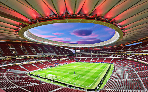 The Atletico Madrid stadium shows a vibrant sunset with colorful clouds above the empty red and white seats, 2K Desktop Wallpaper