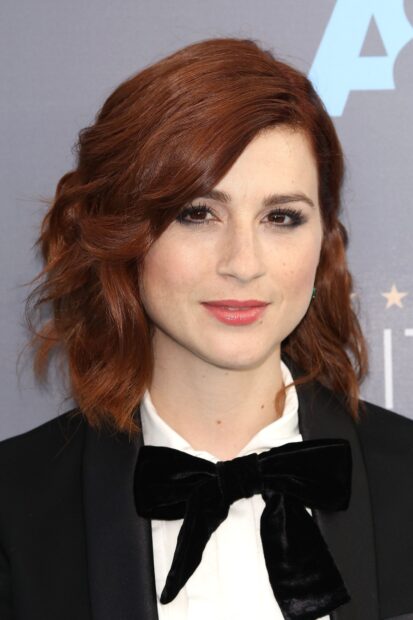 Aya Cash with red hair and black bow tie smiling gently, 2K Desktop Wallpaper
