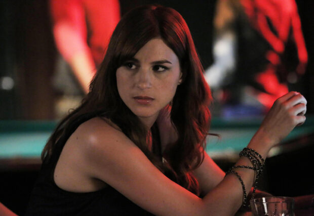 Aya Cash looks focused in a dimly lit setting with red and dark background, 2K Desktop Wallpaper