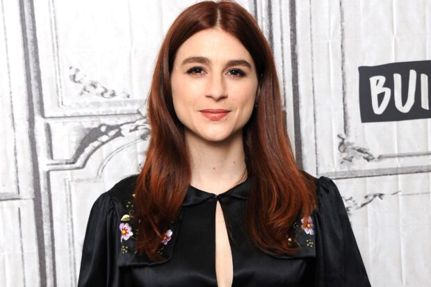 Aya Cash portrait wearing a black dress with floral details smiling at the camera, 2K Desktop Wallpaper