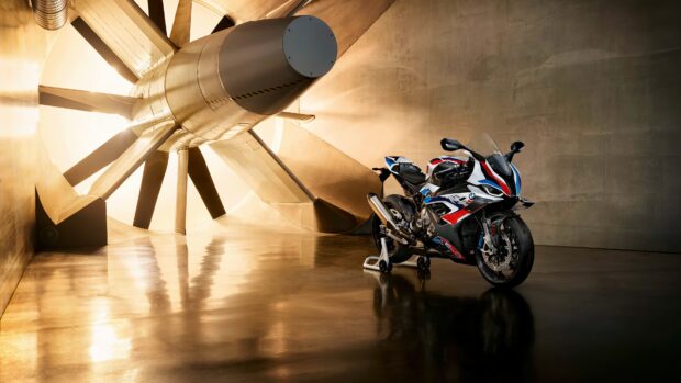 A BMW M 1000 RR motorcycle displayed in a modern studio with large ventilation fan, 4K Desktop Wallpaper